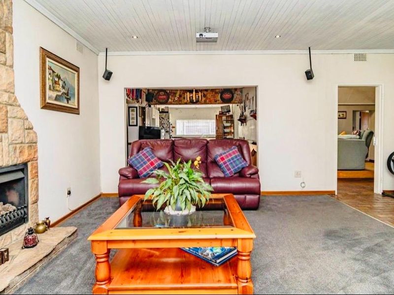 Spacious living room featuring a prominent stone fireplace, tongue and groove ceiling, and integrated audio-visual infrastructure.