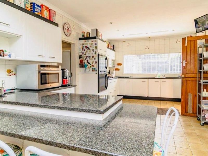 A functional kitchen featuring granite countertops, ample cabinetry, built-in oven and microwave, and tiled flooring, offering a practical layout for daily meal preparation.