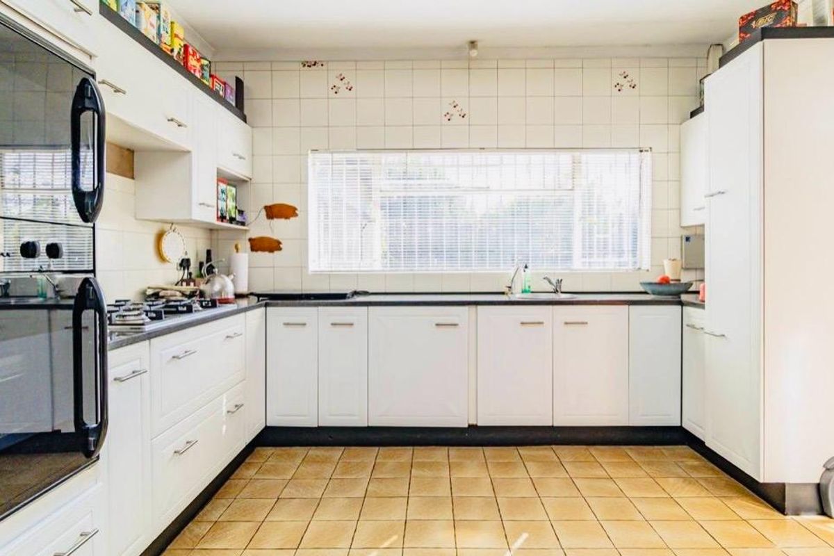 A functional kitchen featuring white cabinetry, built-in oven, gas hob, and tiled finishes, offering a clean layout ready for modern updates.