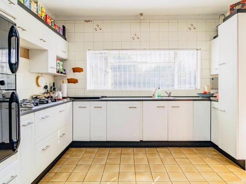 A functional kitchen featuring white cabinetry, built-in oven, gas hob, and tiled finishes, offering a clean layout ready for modern updates.