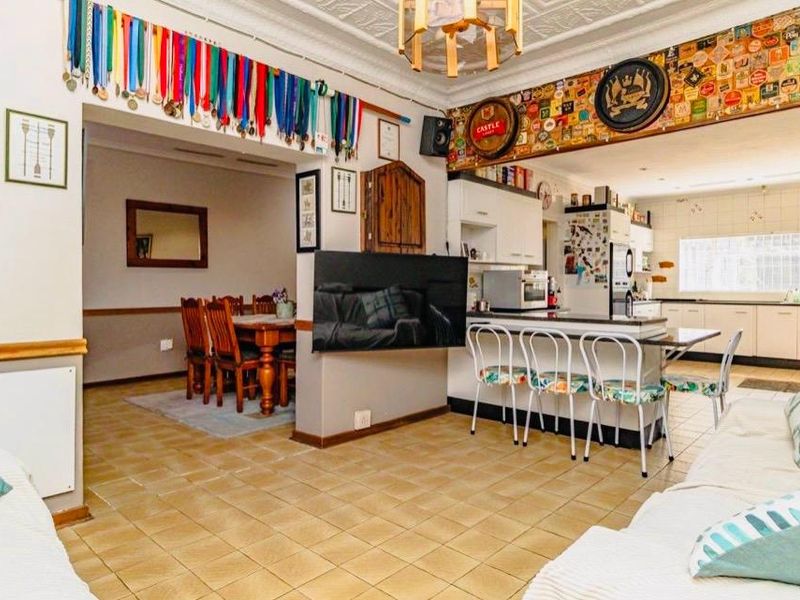 Open-plan living and kitchen area featuring tiled flooring, a central kitchen island, and decorative ceiling molding, offering a functional and connected layout.