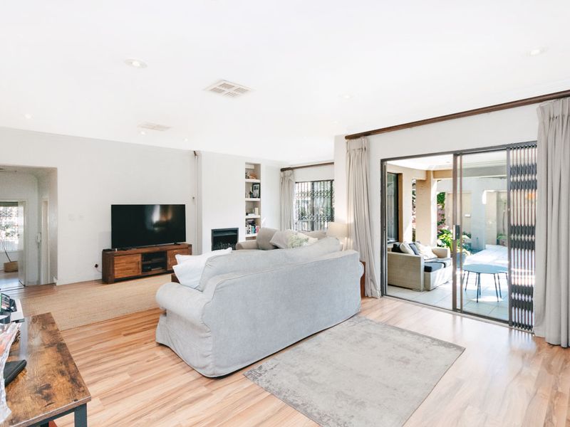 Spacious living room featuring laminate flooring, a built-in fireplace with shelving, and large sliding glass doors providing seamless access to the outdoor patio area.