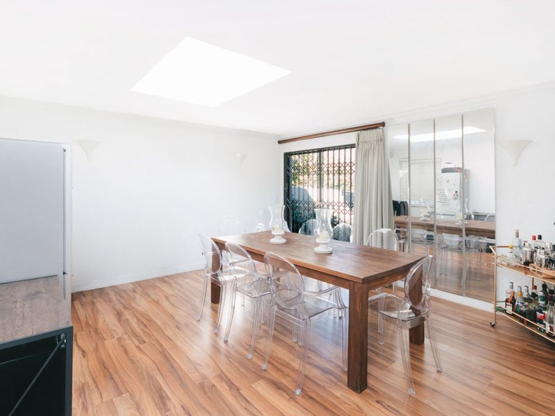 Bright dining room featuring laminate flooring, a large skylight for natural illumination, and mirrored wall panels that enhance the sense of space.