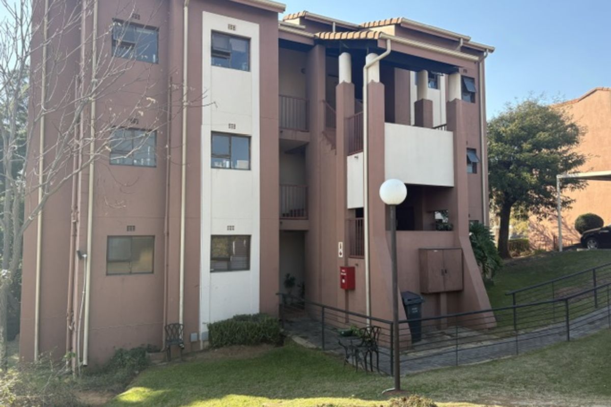 Rear elevation of a multi-story townhouse complex featuring balconies, external staircases, and established communal garden areas.