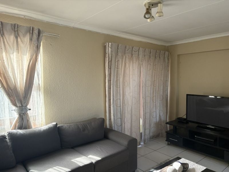 A functional living room featuring tiled flooring and neutral wall finishes, providing a comfortable space for relaxation and entertainment.