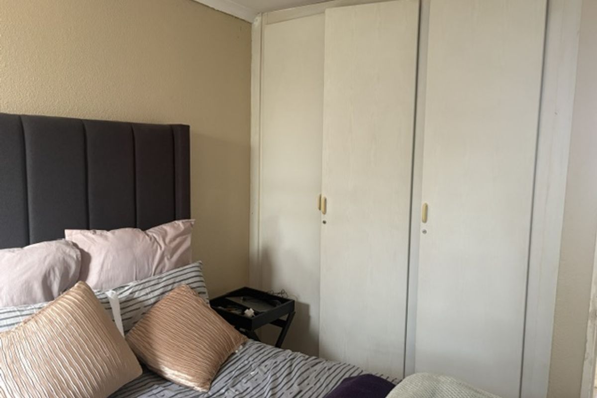 A bedroom featuring built-in cupboards with a neutral wall finish, offering functional storage space within the townhouse.