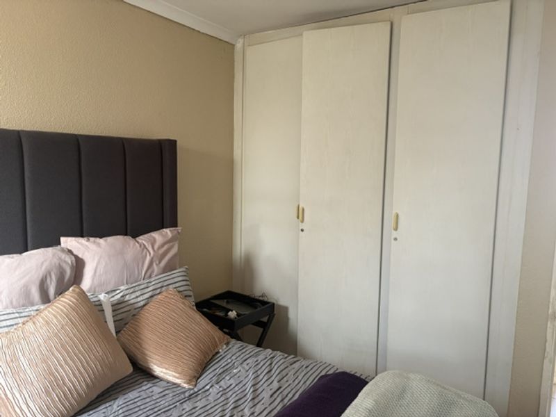 A bedroom featuring built-in cupboards with a neutral wall finish, offering functional storage space within the townhouse.