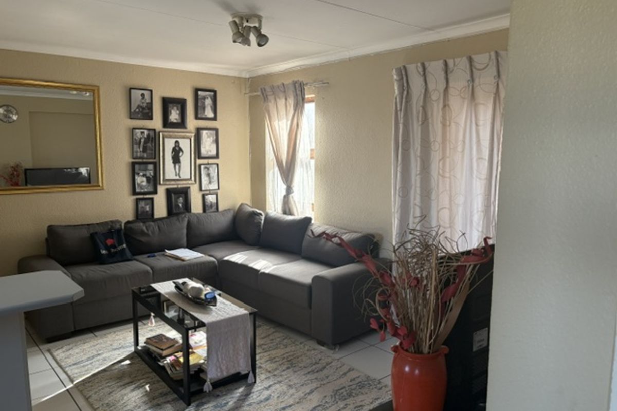 A comfortable living room featuring tiled flooring, coved ceiling cornices, and natural light from the window.