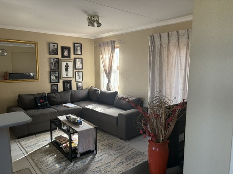 A comfortable living room featuring tiled flooring, coved ceiling cornices, and natural light from the window.