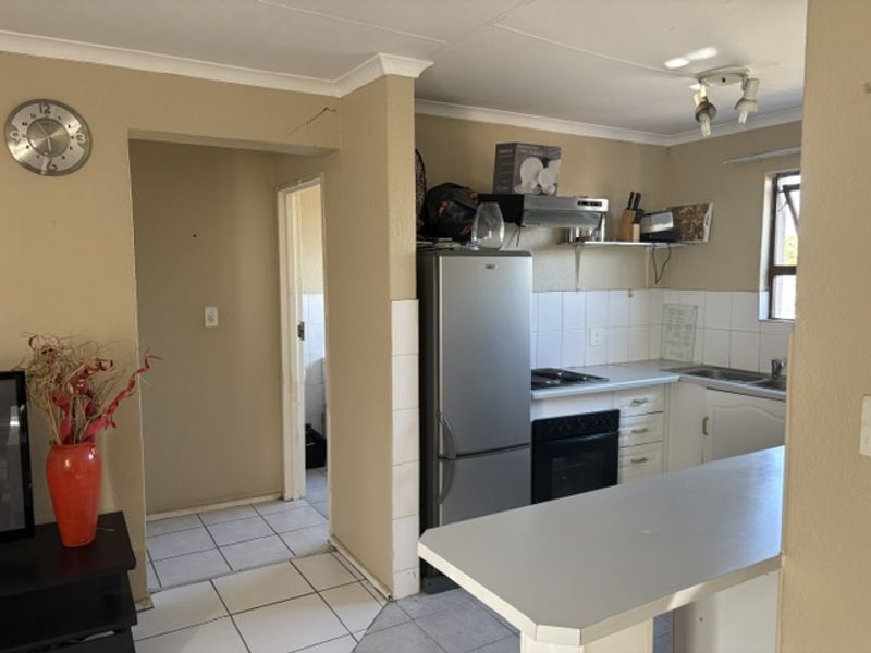 A functional kitchen featuring built-in cabinetry, a breakfast bar, and tiled splashbacks, requiring some cosmetic updates to the wall finishes.