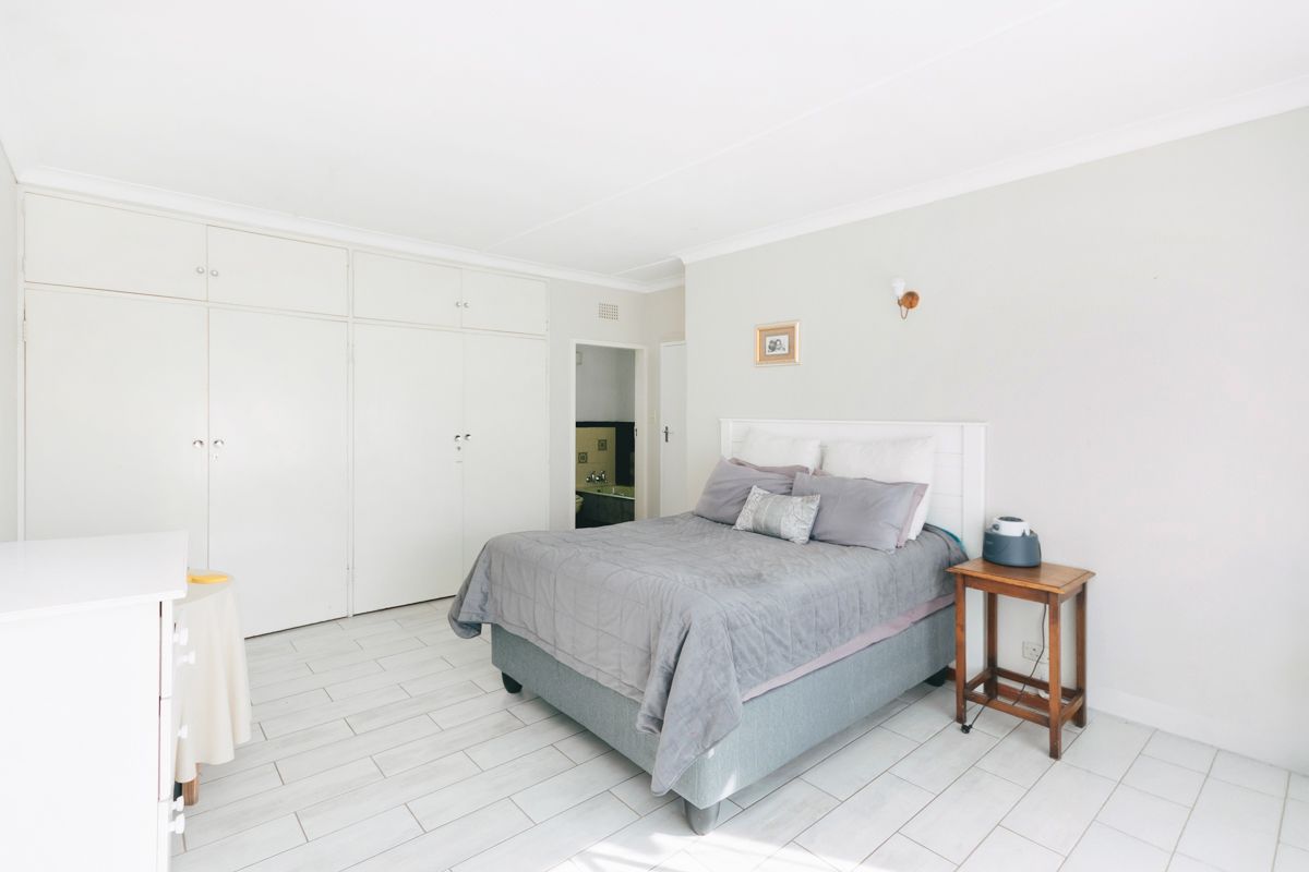 Spacious bedroom featuring built-in cupboards, light-toned tiled flooring, and direct access to an en-suite bathroom.