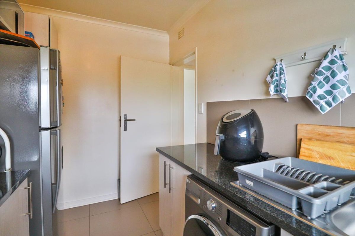 A functional scullery area featuring granite countertops, built-in cabinetry, and tiled flooring, providing additional workspace and utility for the kitchen.