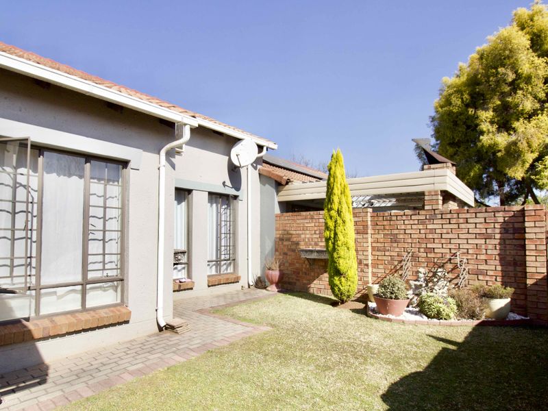 A private rear garden area featuring a paved walkway, brick boundary wall, and established landscaping, providing a functional outdoor space for the property.