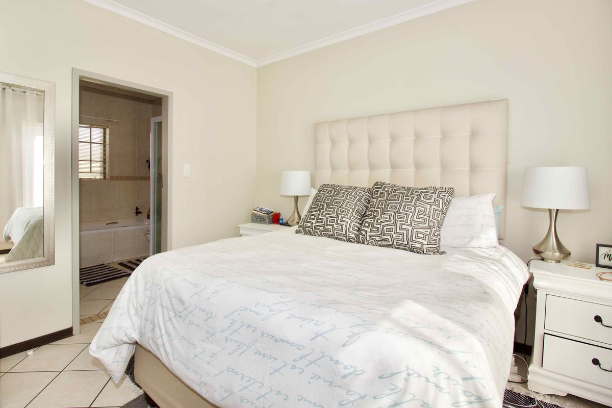 A well-maintained bedroom featuring tiled flooring, coving, and direct access to an en-suite bathroom.