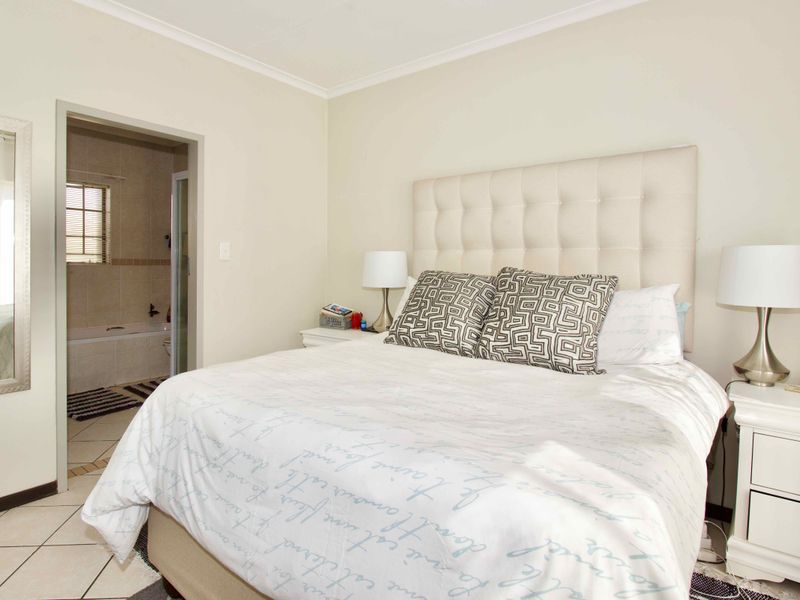 A well-maintained bedroom featuring tiled flooring, coving, and direct access to an en-suite bathroom.