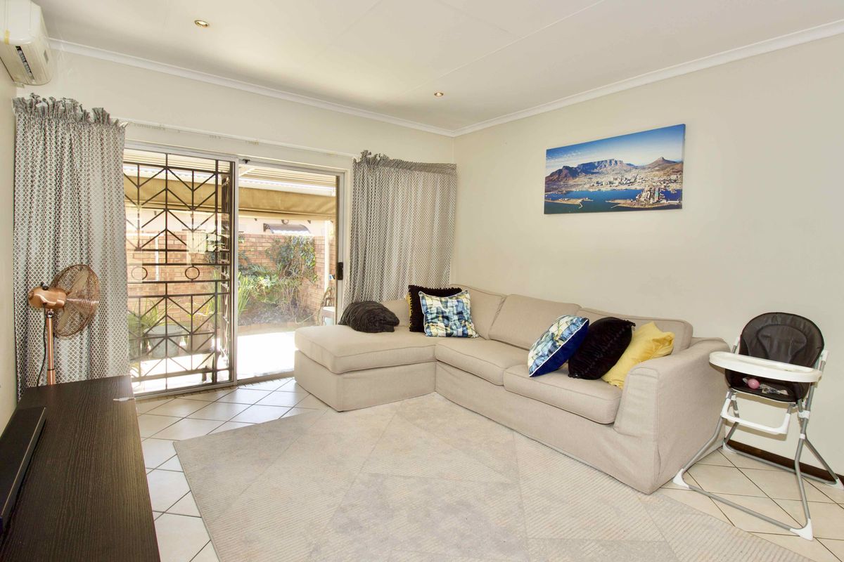 A bright living room featuring tiled flooring, an air conditioning unit, and a sliding glass door providing access to the outdoor area.