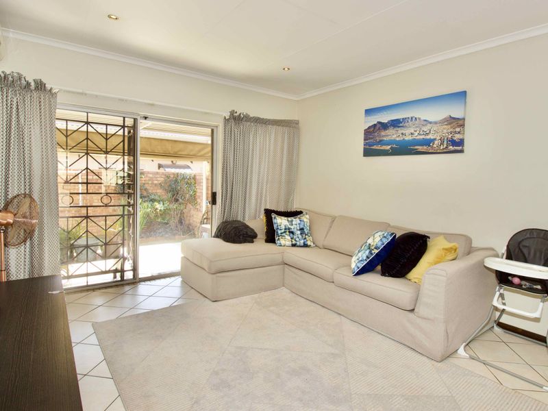 A bright living room featuring tiled flooring, an air conditioning unit, and a sliding glass door providing access to the outdoor area.