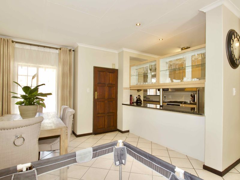Open-plan living and dining area featuring tiled floors, recessed lighting, and a kitchen with granite countertops and glass-fronted display cabinetry.