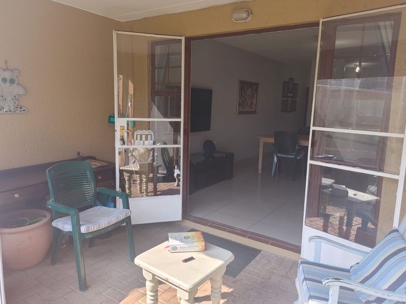 A covered patio area featuring paved flooring and double glass doors providing access to the interior living space.
