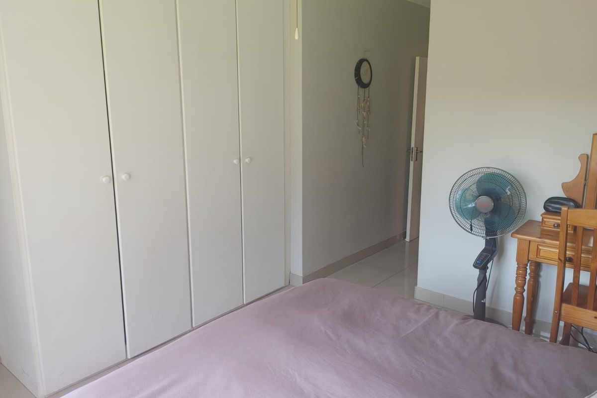 A bedroom featuring built-in cupboards and tiled flooring, offering a functional and neutral space.