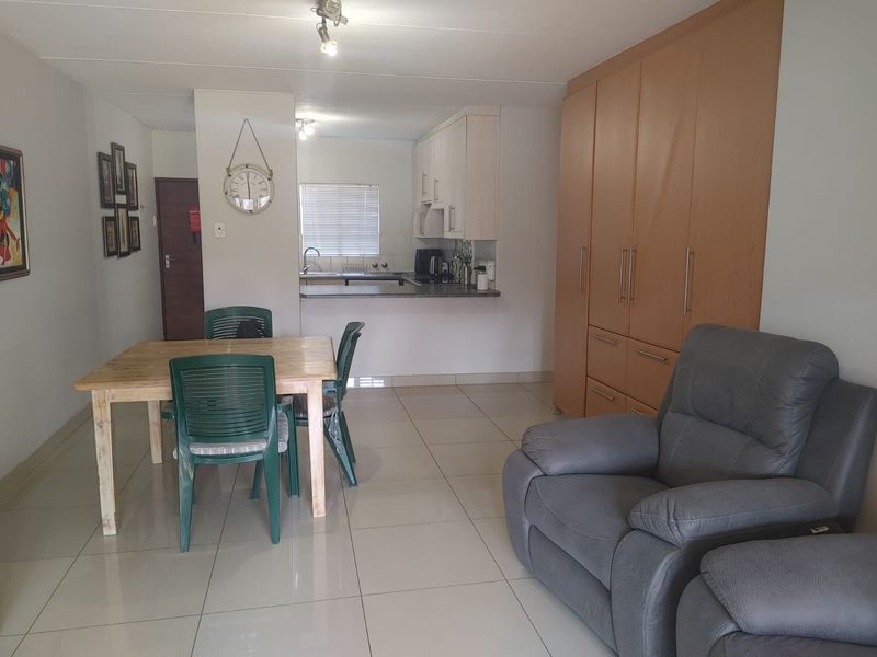 Open plan living and dining area featuring tiled floors, built-in storage cupboards, and a functional kitchen with a breakfast counter.