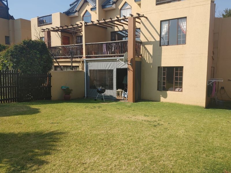 Rear view of the townhouse featuring a private garden, a covered patio area with canvas enclosure, and an upper-level balcony with timber balustrade.