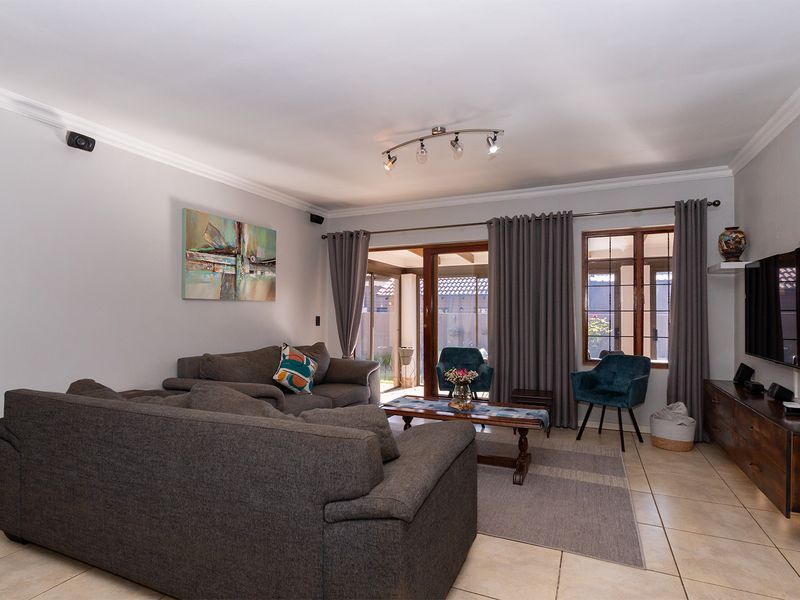 A comfortable living room featuring tiled flooring, coved ceilings, and sliding glass doors that provide access to the outdoor patio area.