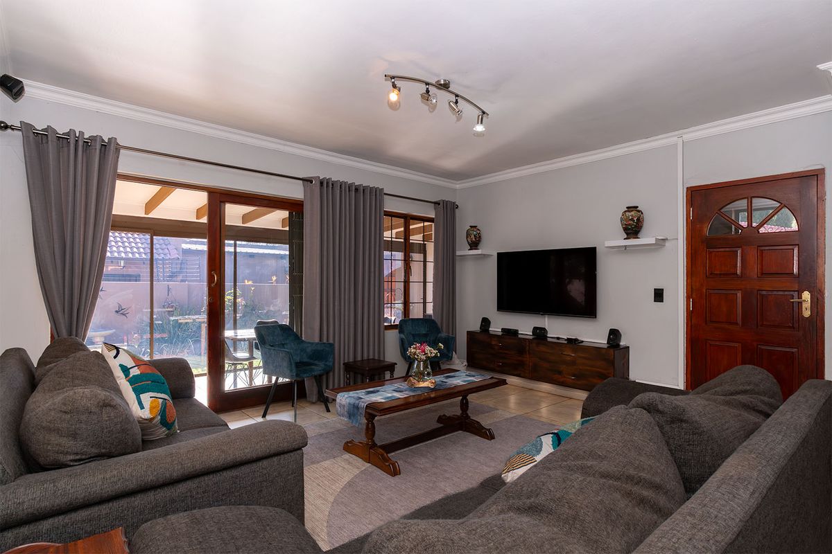 A comfortable living room featuring tiled flooring, ceiling coving, and a sliding glass door providing access to the outdoor patio area.