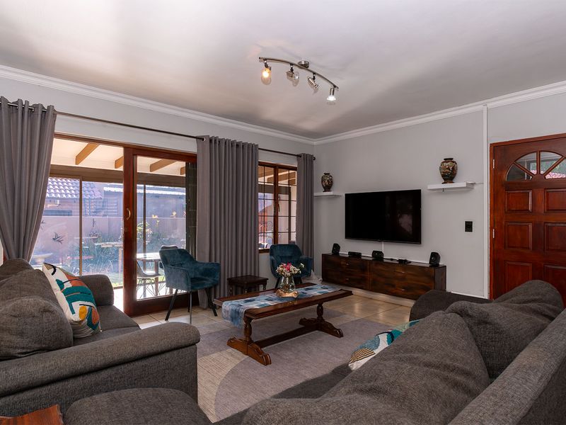A comfortable living room featuring tiled flooring, ceiling coving, and a sliding glass door providing access to the outdoor patio area.