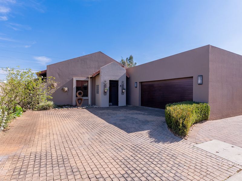 Front elevation of a cluster home featuring a paved driveway, double garage with automated door, and well-maintained exterior finishes.