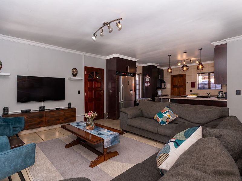 Open-plan living area featuring a kitchen with granite countertops, island, and tiled flooring, seamlessly flowing into a comfortable lounge space.
