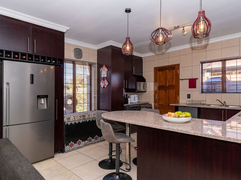 A well-appointed kitchen featuring dark wood cabinetry, granite countertops, a built-in wine rack, and modern pendant lighting, creating a functional and stylish cooking space.
