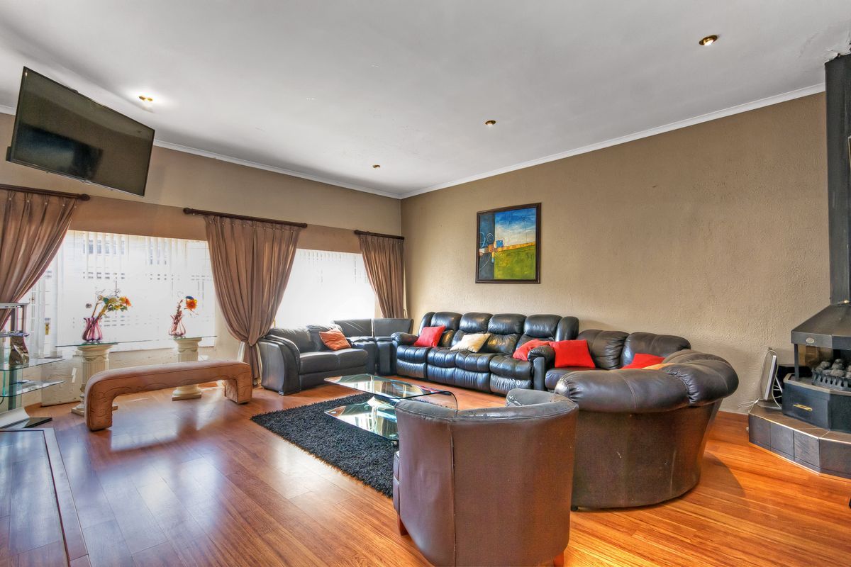 Spacious living room featuring warm wood laminate flooring, a built-in fireplace, and recessed lighting, offering a comfortable and inviting atmosphere.