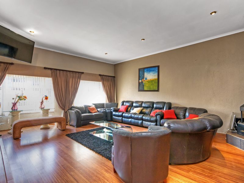 Spacious living room featuring warm wood laminate flooring, a built-in fireplace, and recessed lighting, offering a comfortable and inviting atmosphere.