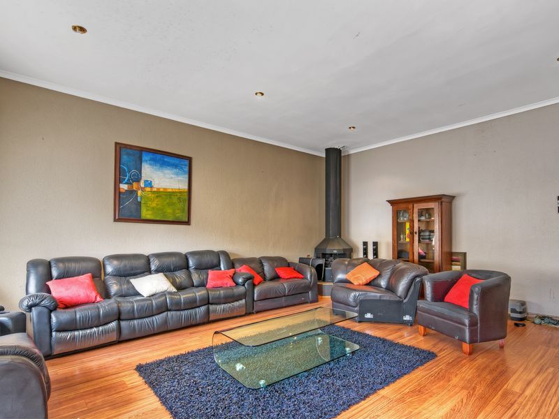 Spacious living room featuring laminate flooring, recessed downlights, and a central freestanding fireplace.