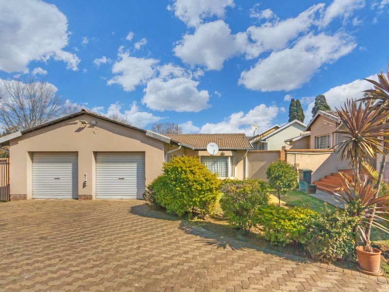 Front view of the property featuring a double garage, paved driveway, and landscaped garden area with brick stairs leading to the entrance.