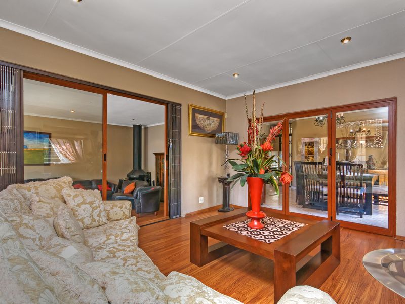 A spacious living room featuring laminate flooring, recessed lighting, and large sliding glass doors that provide views into adjacent living and dining areas.