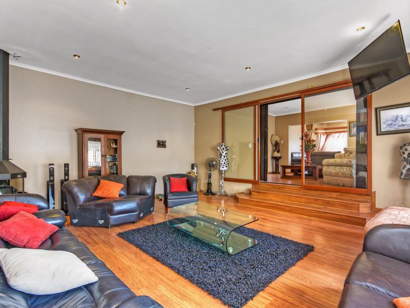 Spacious living room featuring laminate flooring, a wood-burning fireplace, and large sliding glass doors leading to an adjacent room.