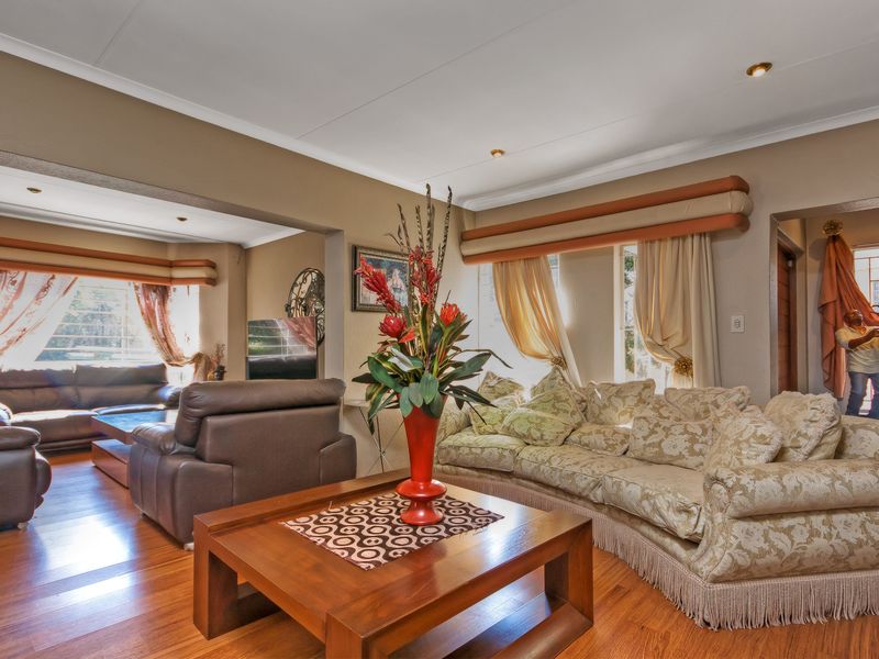 Spacious living room featuring laminate flooring, recessed downlighting, and a coved ceiling, offering a comfortable and well-lit area for relaxation.