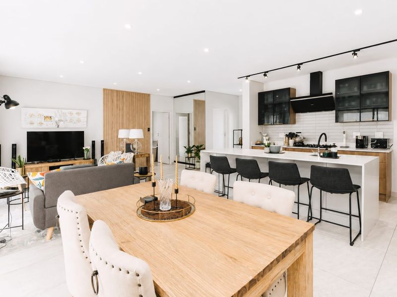 Modern open-plan living area featuring a sleek kitchen with island, contemporary cabinetry, and integrated appliances, seamlessly flowing into the dining and lounge spaces.