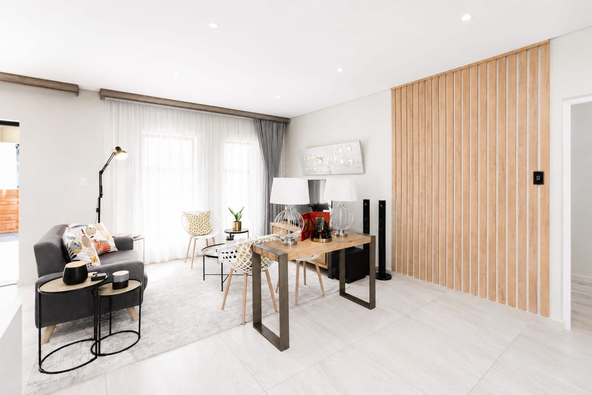 Modern living room featuring light-toned tiled flooring, recessed downlighting, and a contemporary timber slat feature wall.