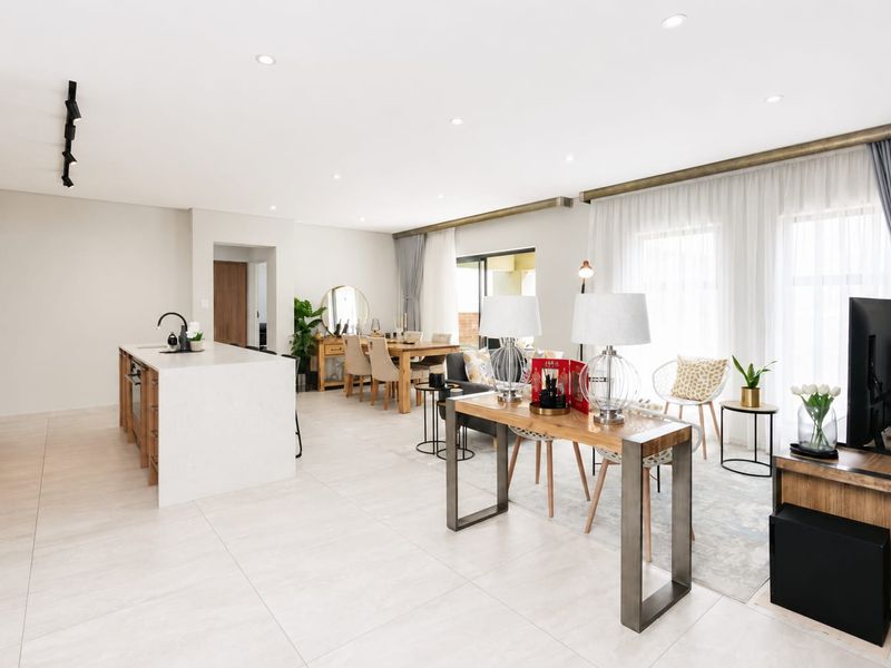 Spacious open-plan living area featuring a modern kitchen with a stone island, recessed lighting, and large windows with elegant curtain treatments.