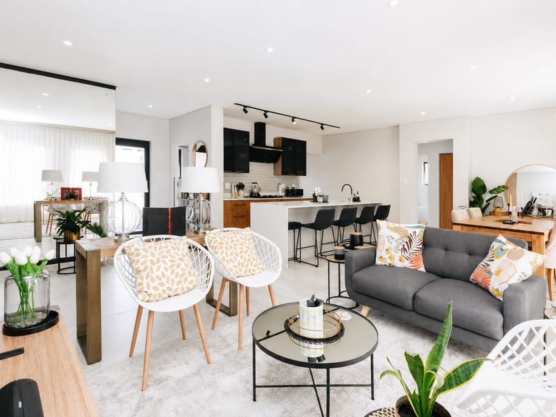 A modern open-plan living and kitchen area featuring a central island, sleek cabinetry, recessed lighting, and contemporary tiled flooring throughout.