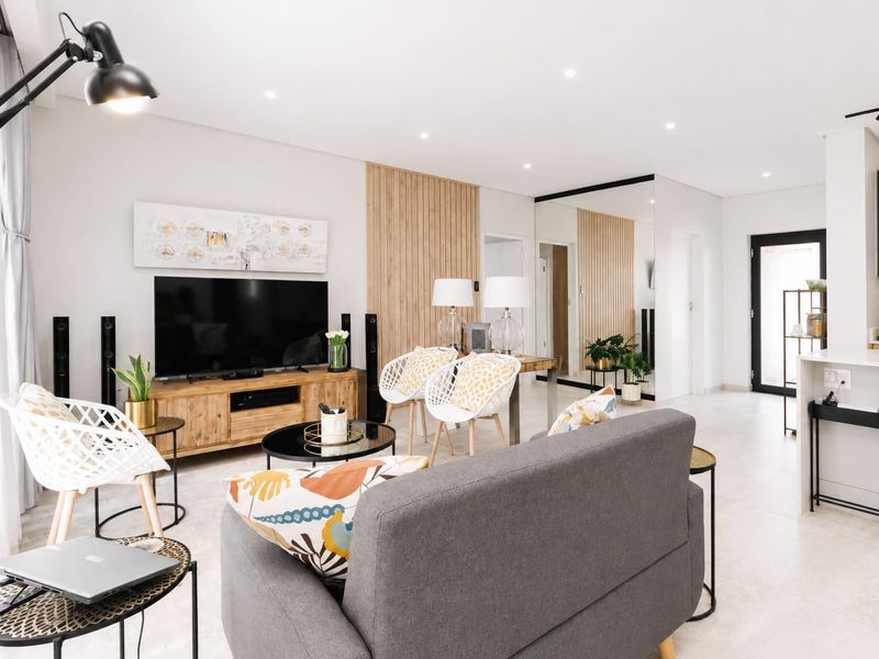 Modern open-plan living area featuring a timber slat feature wall, recessed lighting, tiled floors, and a sleek kitchen island with integrated cabinetry.