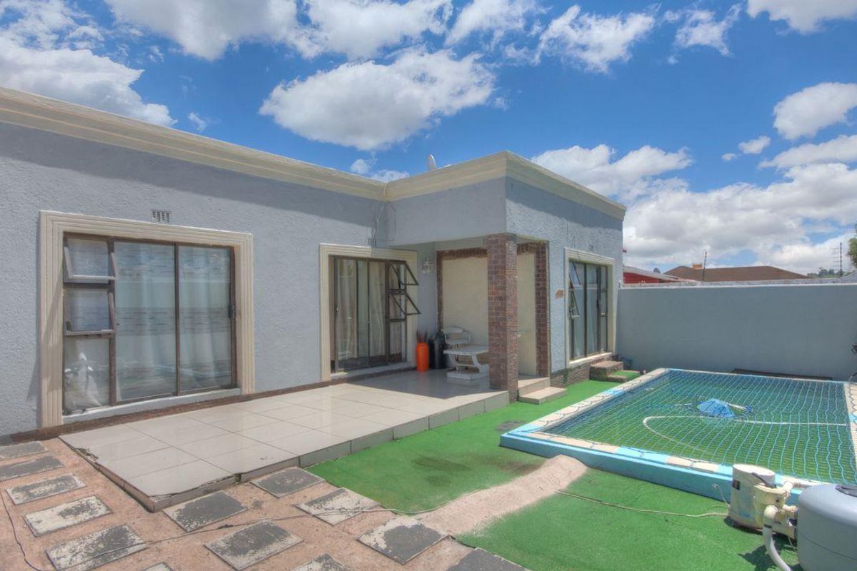 Rear exterior view featuring a swimming pool, tiled patio area, and sliding glass doors providing access to the home.