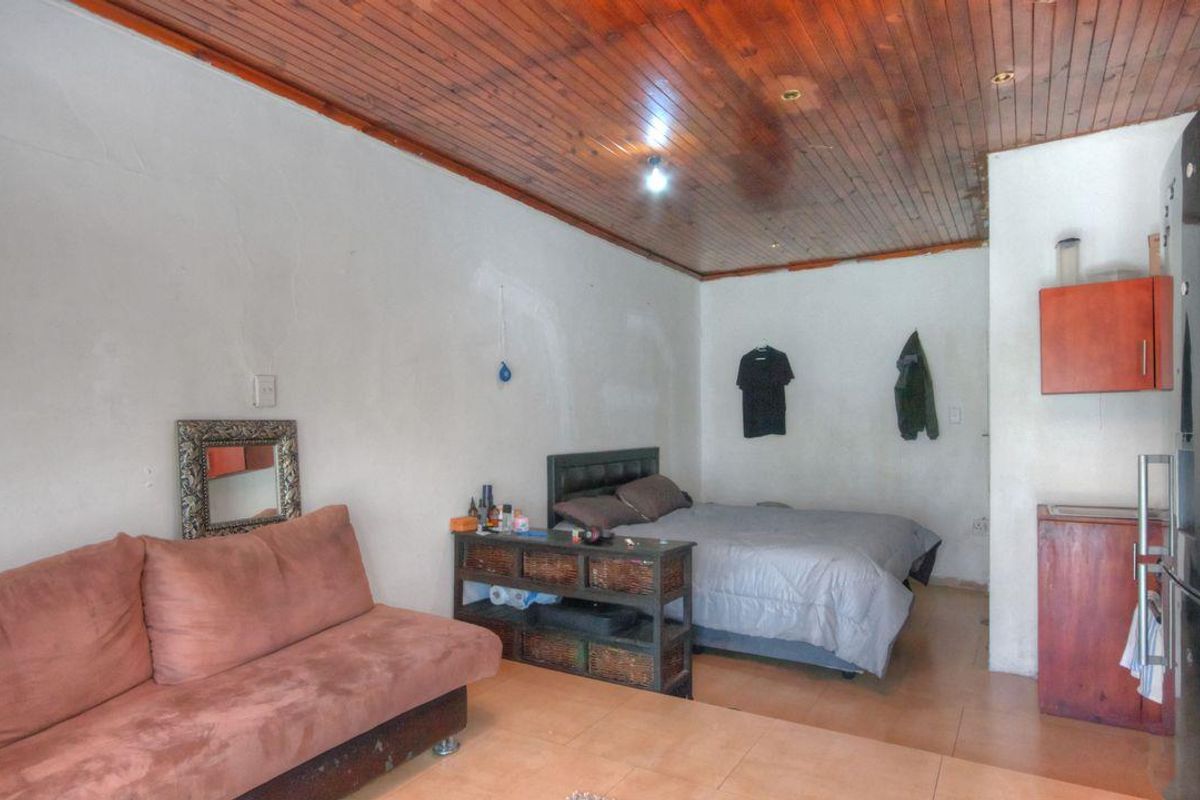 Open plan living and sleeping area featuring timber tongue and groove ceilings and tiled flooring, offering a functional layout for compact living.