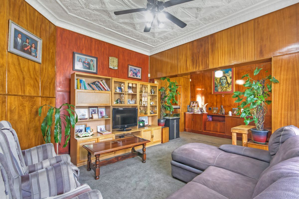 Spacious living room featuring classic wood wall paneling and an ornate decorative plaster ceiling with a central ceiling fan.