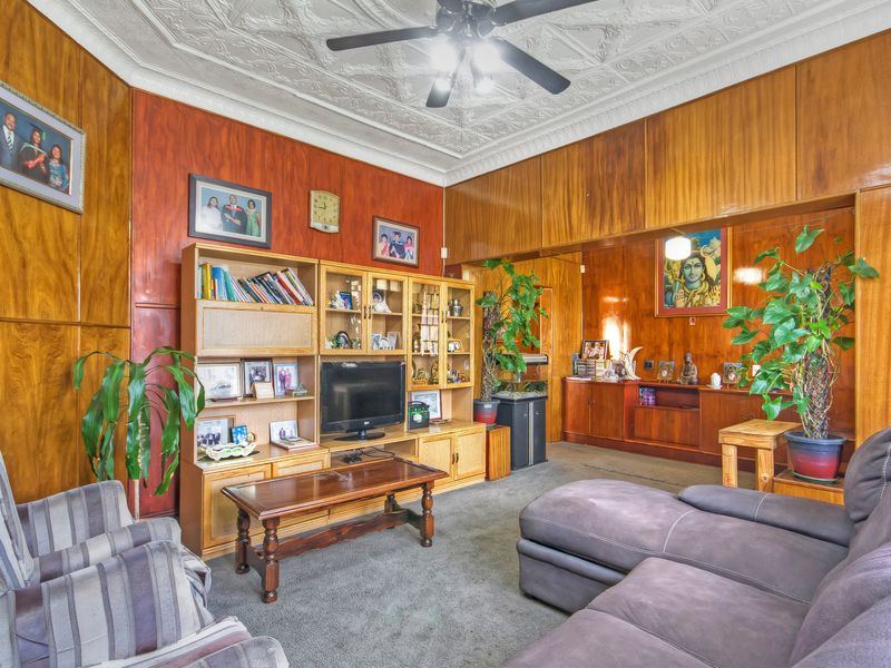 Spacious living room featuring classic wood wall paneling and an ornate decorative plaster ceiling with a central ceiling fan.