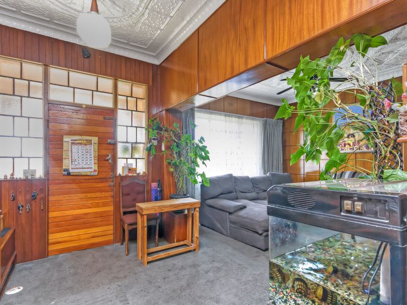 Living room featuring classic wood paneling, a decorative pressed metal ceiling, and a timber entrance door with leaded glass detailing.
