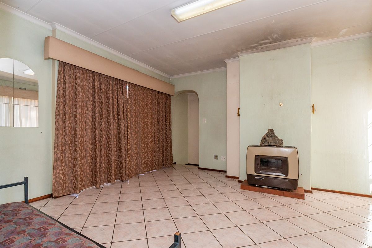 Spacious living room featuring tiled flooring, a built-in fireplace, and an archway leading to adjacent areas. The space is ready for a modern update.